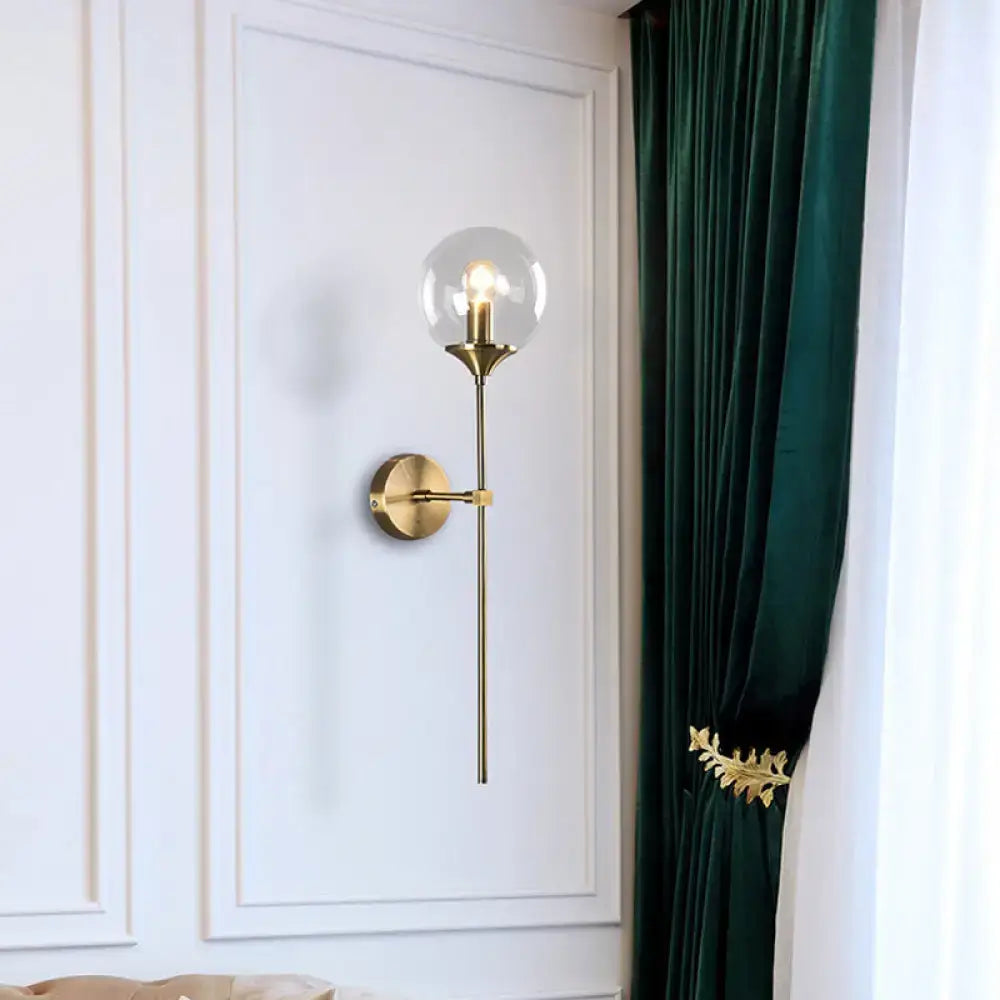 Gold-toned postmodern wall sconce with smoke grey glass globe and slender stem for e26 e27 bulb use in bedroom