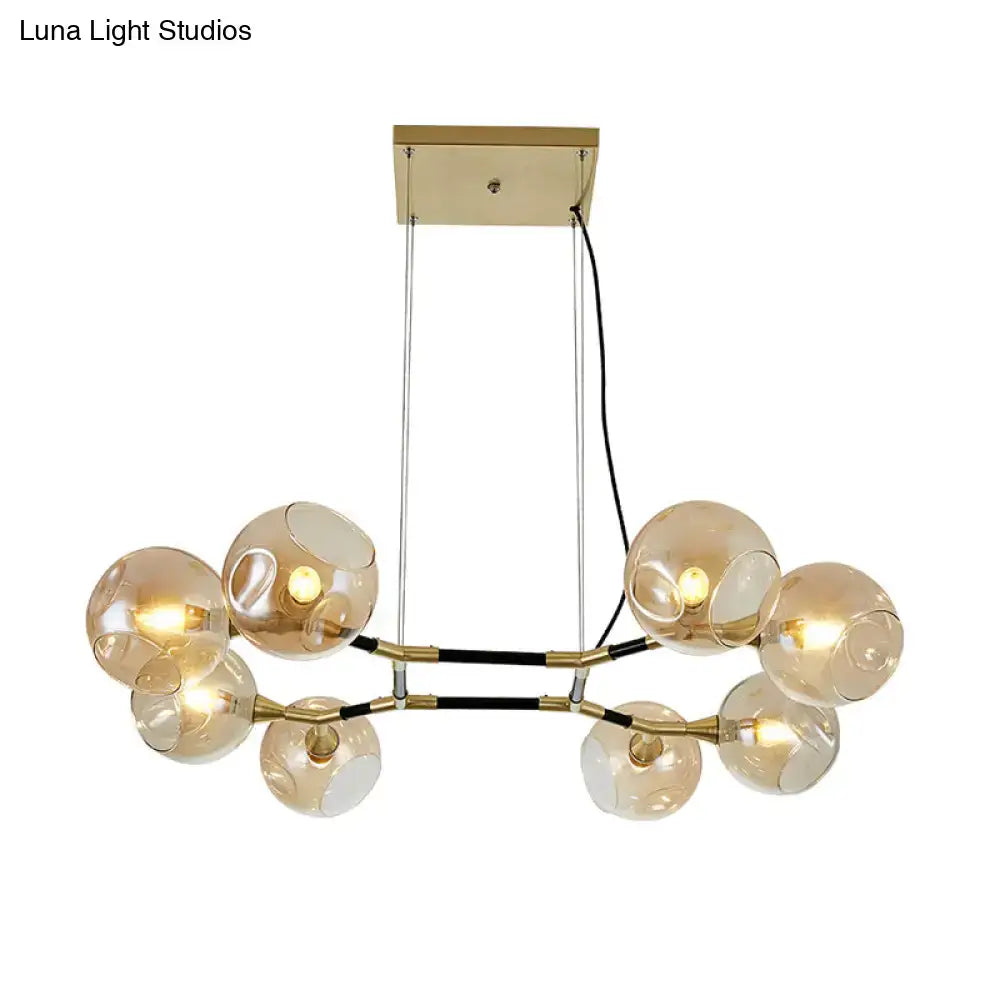 Modern gold-toned DecorBites™ postmodern island lighting with amber ball glass globe shades and adjustable black cords