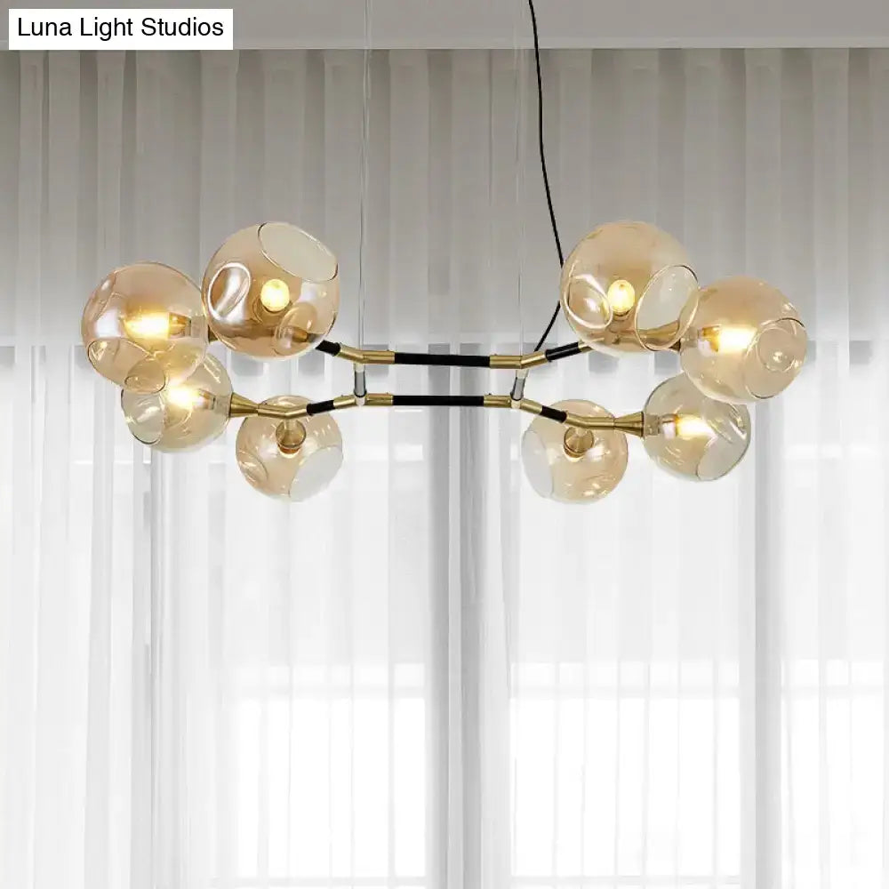 Modern gold-toned DecorBites island lighting featuring amber ball glass globes and black structural accents with adjustable cord