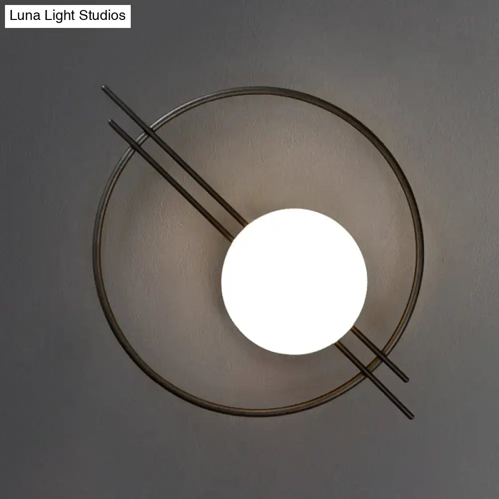 Postmodern black brass sconce light with a circular metal frame and white glass globe for bedroom illumination