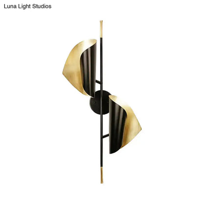 Modern two-light wall light with sleek black and gold metallic finish and sculpted ribbed leaf shades for staircase use