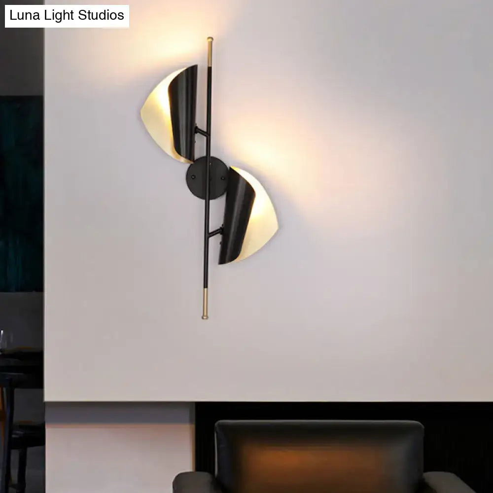 Modern black and brass wall light with two curved illuminated shades for staircase lighting in a postmodern style