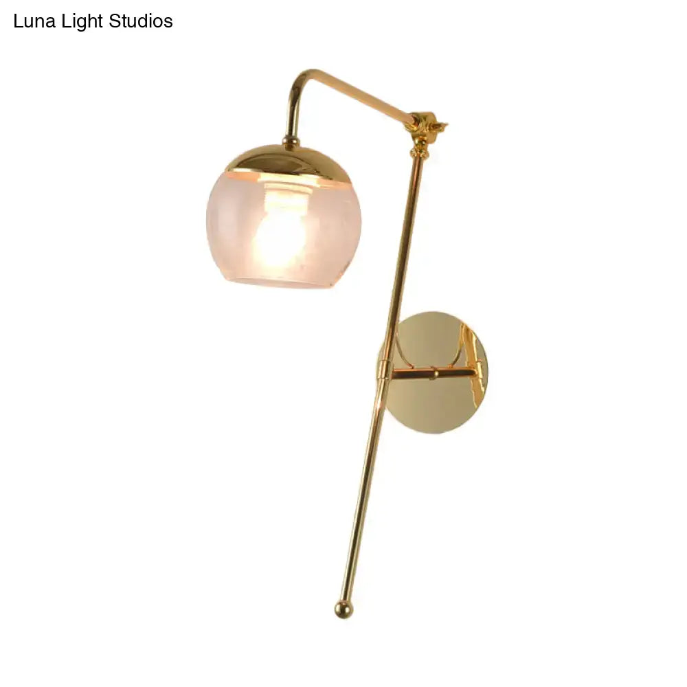 Brass-finished swing arm wall sconce with a spherical frosted glass shade for modern bedroom lighting
