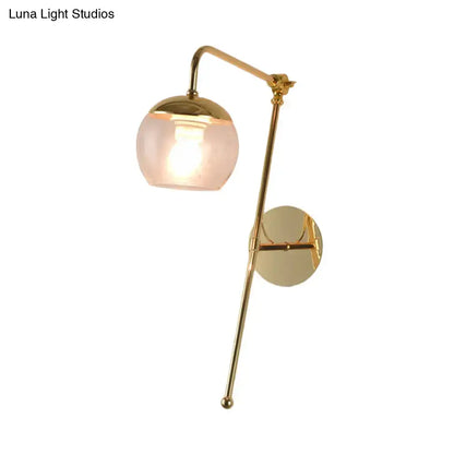 Brass-finished swing arm wall sconce with a spherical frosted glass shade for modern bedroom lighting