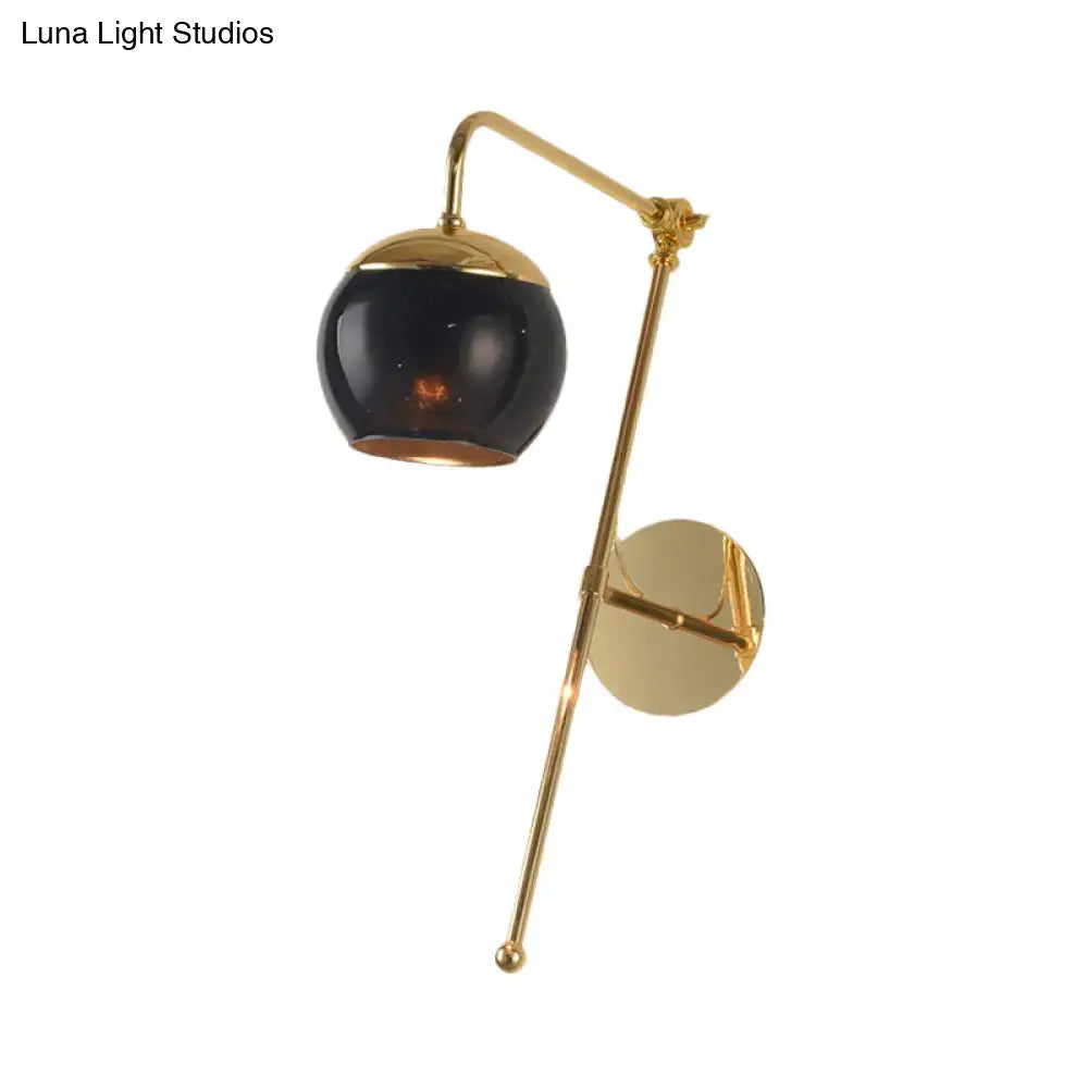 Postmodern gold finish swing arm wall sconce with glossy black spherical glass shade and clear glass elements for bedroom lighting