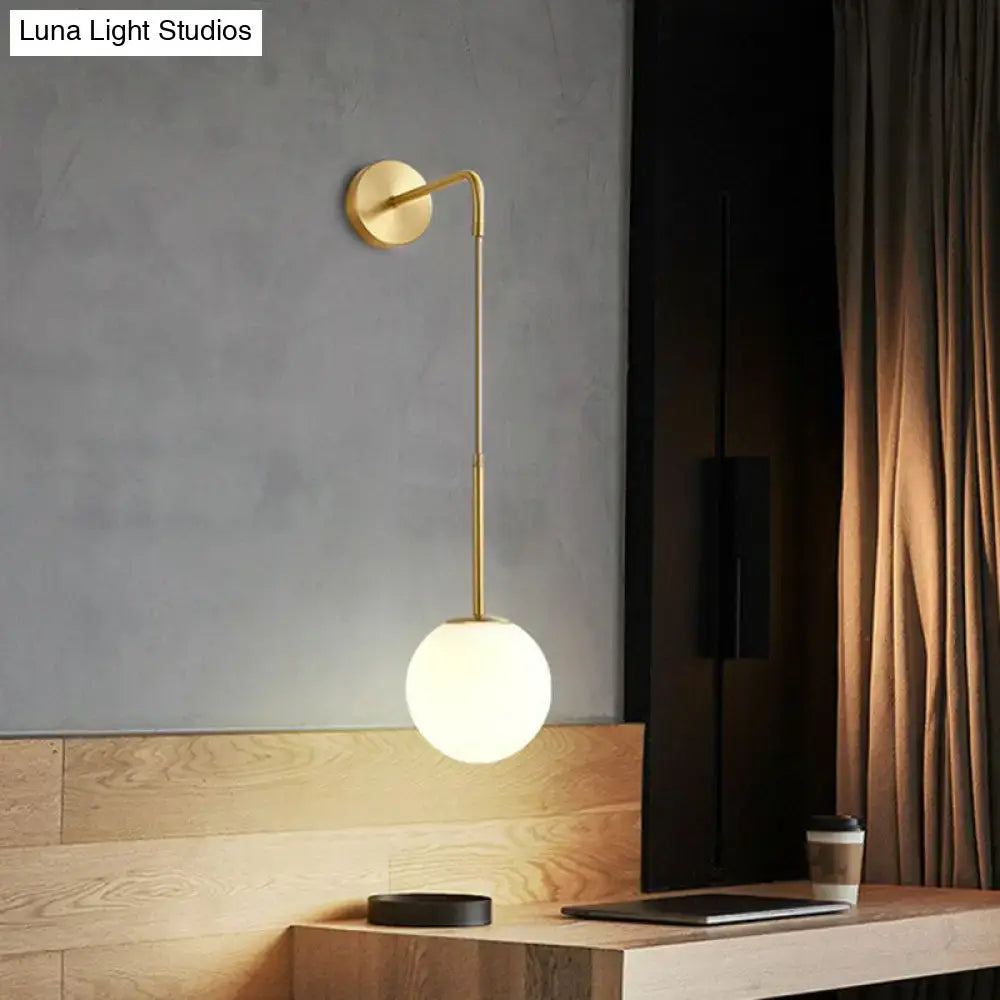 Gold-finished postmodern wall lamp with a slender curved arm and frosted glass globe for bedroom lighting