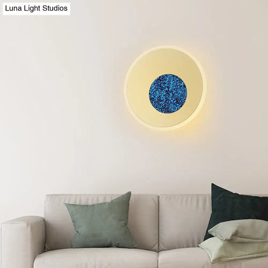 Postmodern blue round sconce light fixture with glowing cream ring and textured sparkling blue center for bedroom use