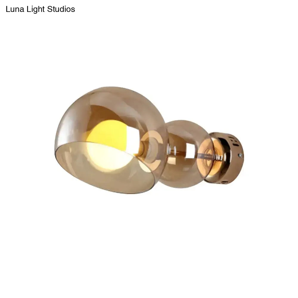 Modern wall lamp with amber glass shade and brass metallic bracket designed as a postmodern bedroom sconce light