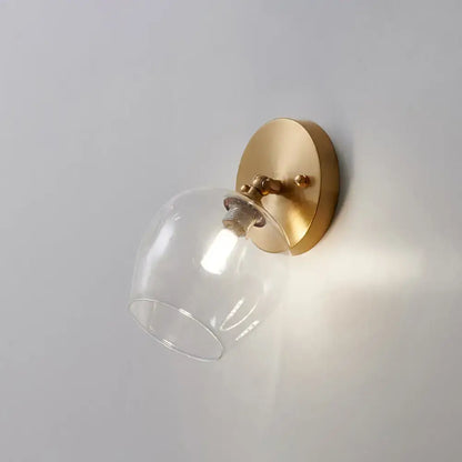 Postmodern brass and glass wall sconce with gold-toned finish and clear glass dome shade light bulb included