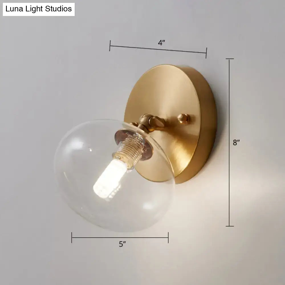 Postmodern brass and glass wall sconce with clear globe light type and bulb included for bedroom use