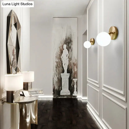 Postmodern gold-toned brass and glass wall sconce with frosted spherical shades light type bulb included