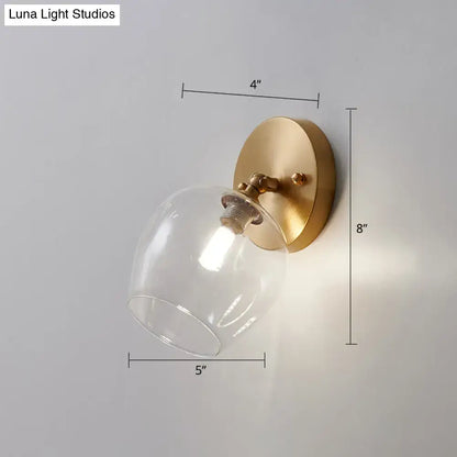 Postmodern brass and glass wall sconce with gold-toned finish and clear glass dome light type bulb included