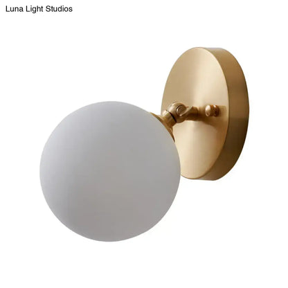 A postmodern brass and glass wall sconce with frosted globe light type and bulb included for bedroom use