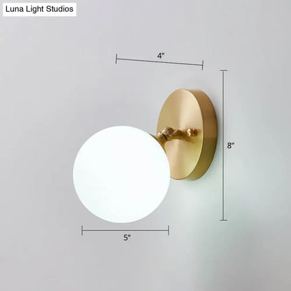 Postmodern brass and glass wall sconce with gold finish and frosted white spherical shade light type bulb included