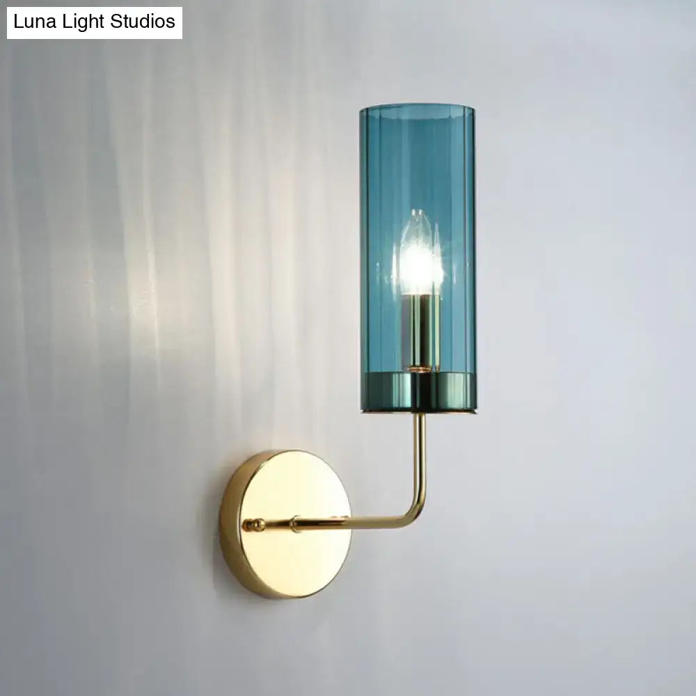 A postmodern brass finish wall lamp with a tall teal smoked glass cylinder and an exposed e12 e14 bulb