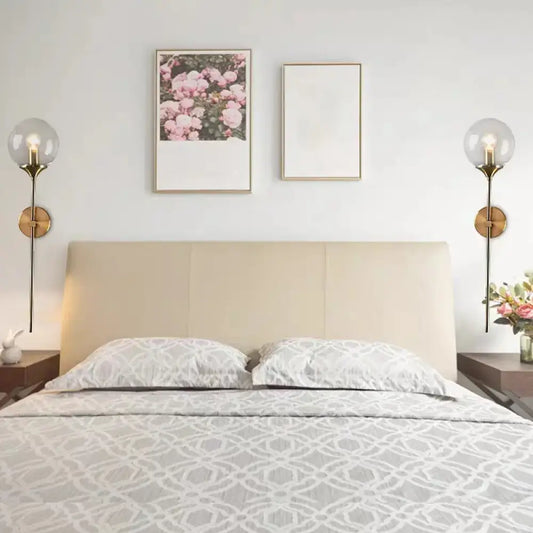 Beige upholstered bed with gray and white geometric duvet illuminated by postmodern brass pencil arm wall lamp bedroom sconce