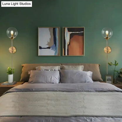 Postmodern brass pencil arm wall lamp with gold-toned spherical glass globes for bedroom sconce lighting