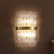 A postmodern crystal rod wall light fixture with clear textured glass tubes and a gold-toned brass band sconce