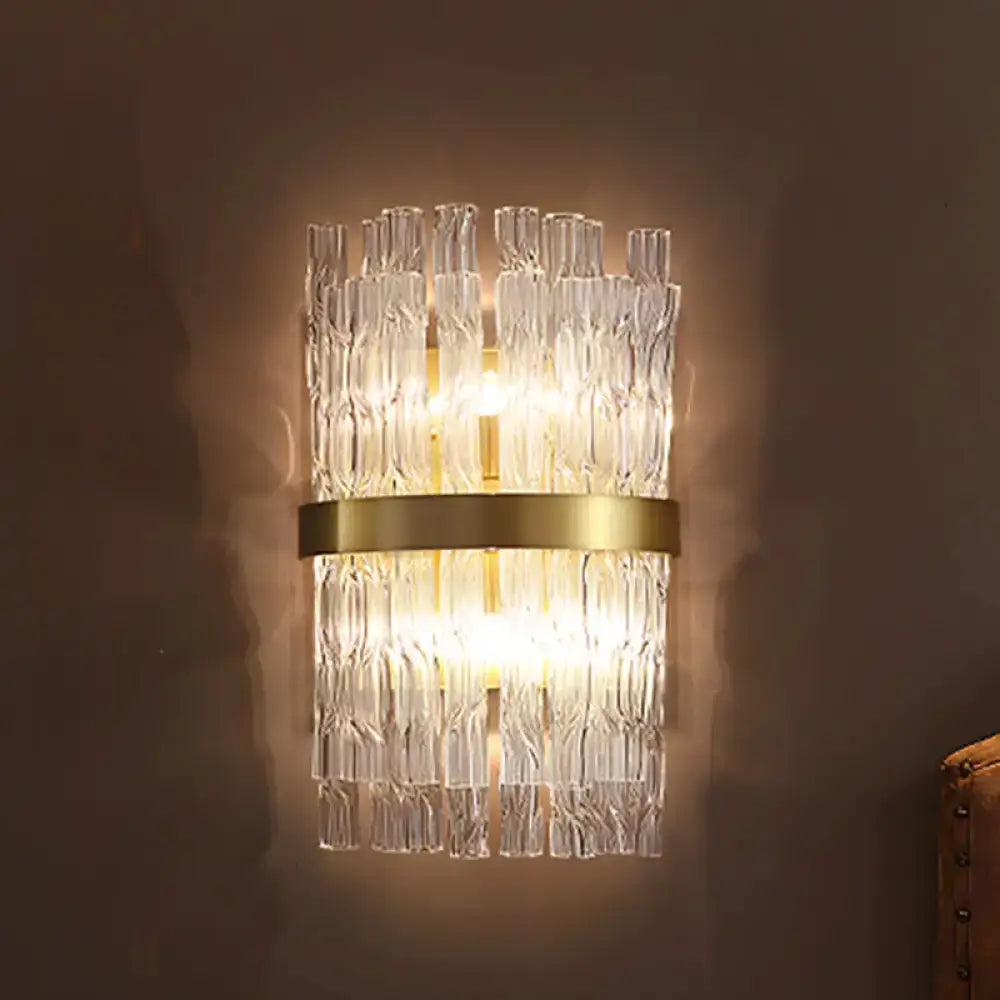 A postmodern crystal rod wall light fixture with clear textured glass tubes and a gold-toned brass band sconce