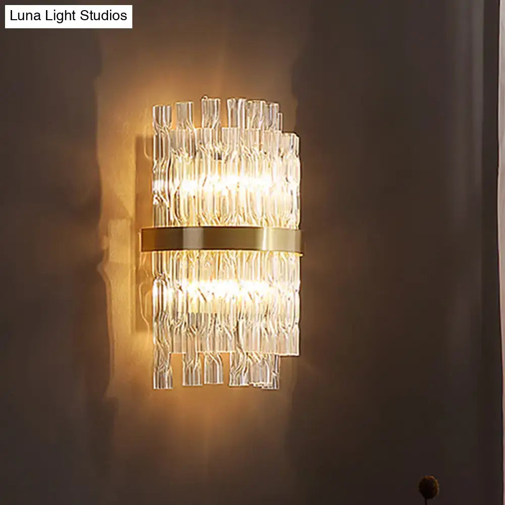 A postmodern crystal rod wall light fixture with clear textured glass tubes and a central brass band for bedroom sconce use