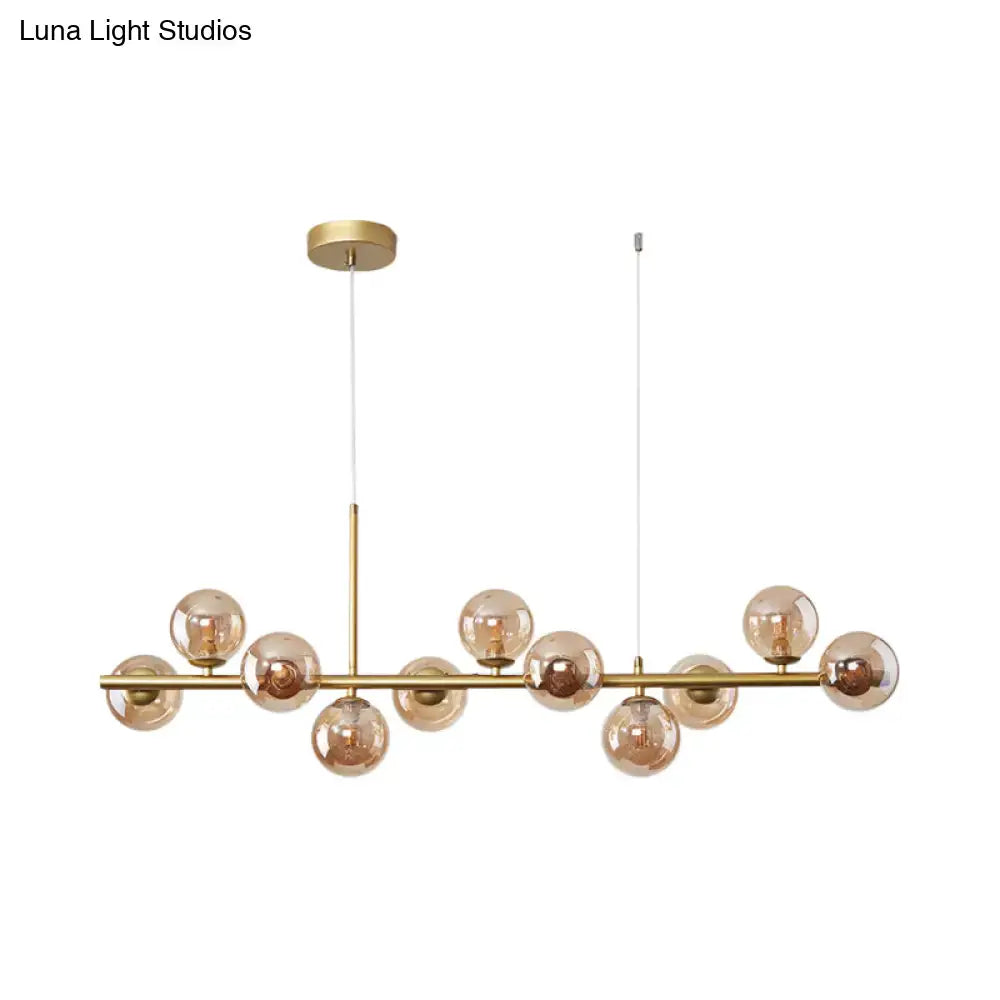 Gold-toned DecorBites™ postmodern pendant light with amber glass globe bulbs on a sleek horizontal bar for kitchen use