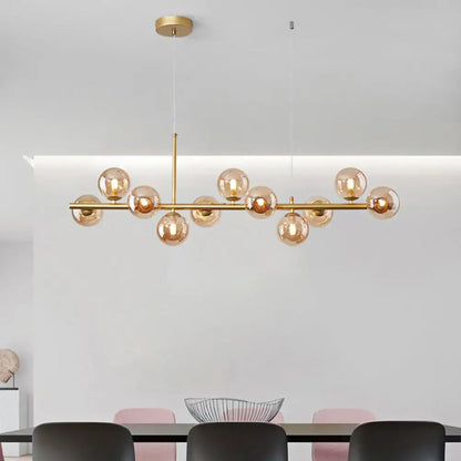 Gold-toned modern pendant light with amber glass globes on a sleek horizontal bar from DecorBites™ for kitchen use