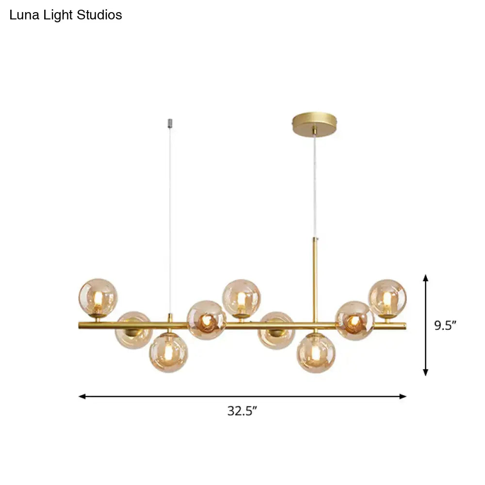 Gold-toned DecorBites postmodern pendant light with amber glass globe bulbs on a horizontal bar for kitchen use