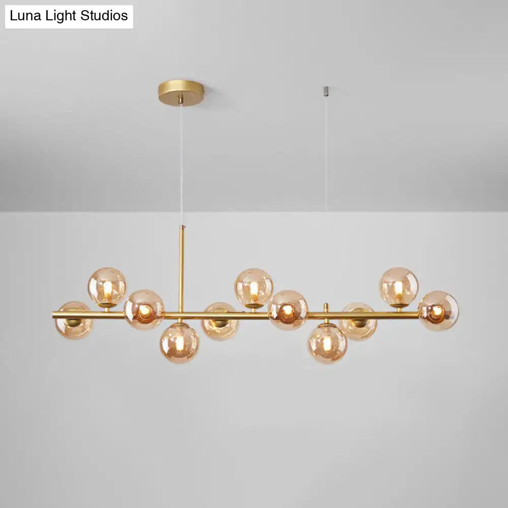 Gold-toned DecorBites™ postmodern glass ball pendant light with amber globes on horizontal bar for kitchen lighting