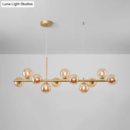 Gold-toned DecorBites™ postmodern glass ball pendant light with amber globes on horizontal bar for kitchen lighting