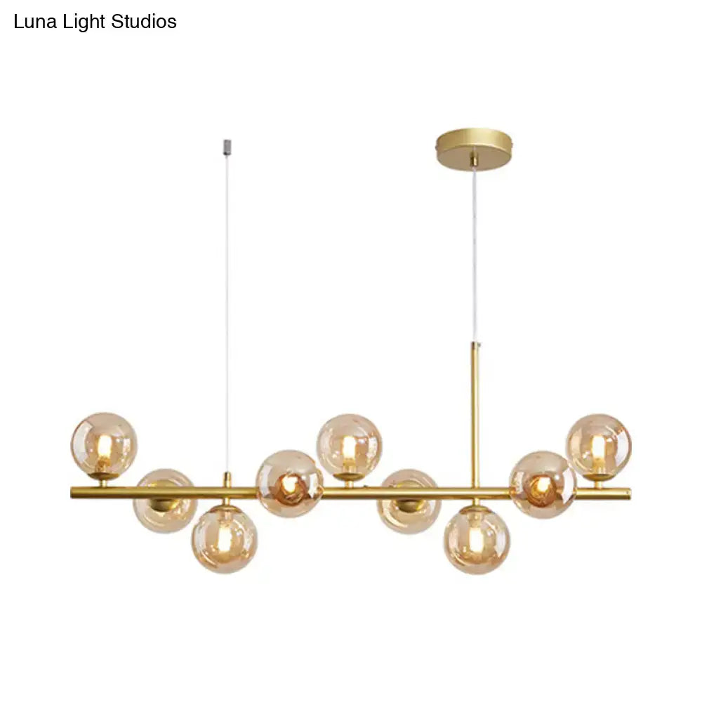 Gold-toned decorbites postmodern pendant light with amber glass globe bulbs and horizontal bar for kitchen use