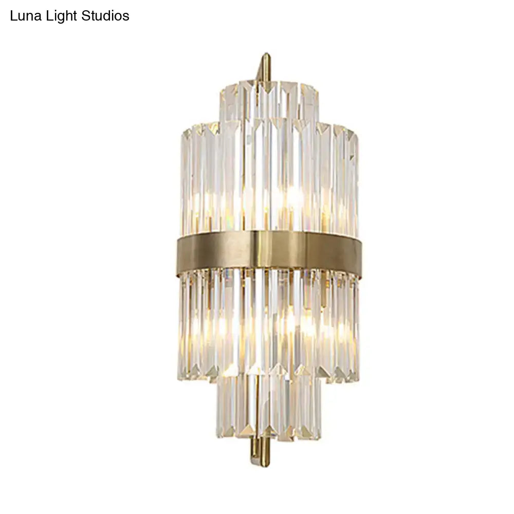 A postmodern gold direct wired electric wall sconce with a brushed brass frame and tiered crystal glass rods