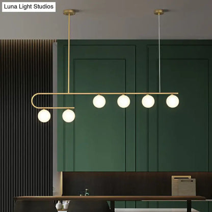 Modern brass DecorBites island pendant light with five frosted ivory glass globes in a sleek curved LED design