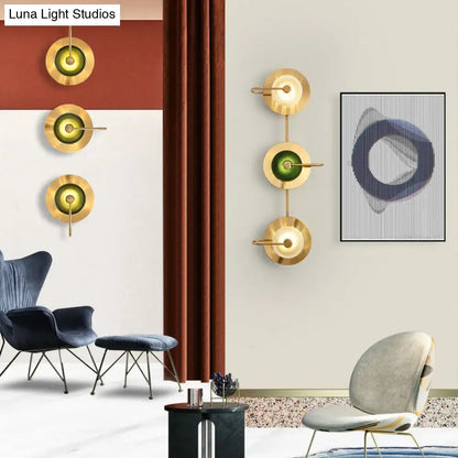 Postmodern gold wall sconce with olive glass disc and minimalist design as a wall mounted lamp for living room