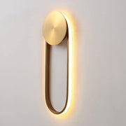 Modern gold-toned direct wired wall lamp with oval top plate and glowing led strip for bedroom lighting