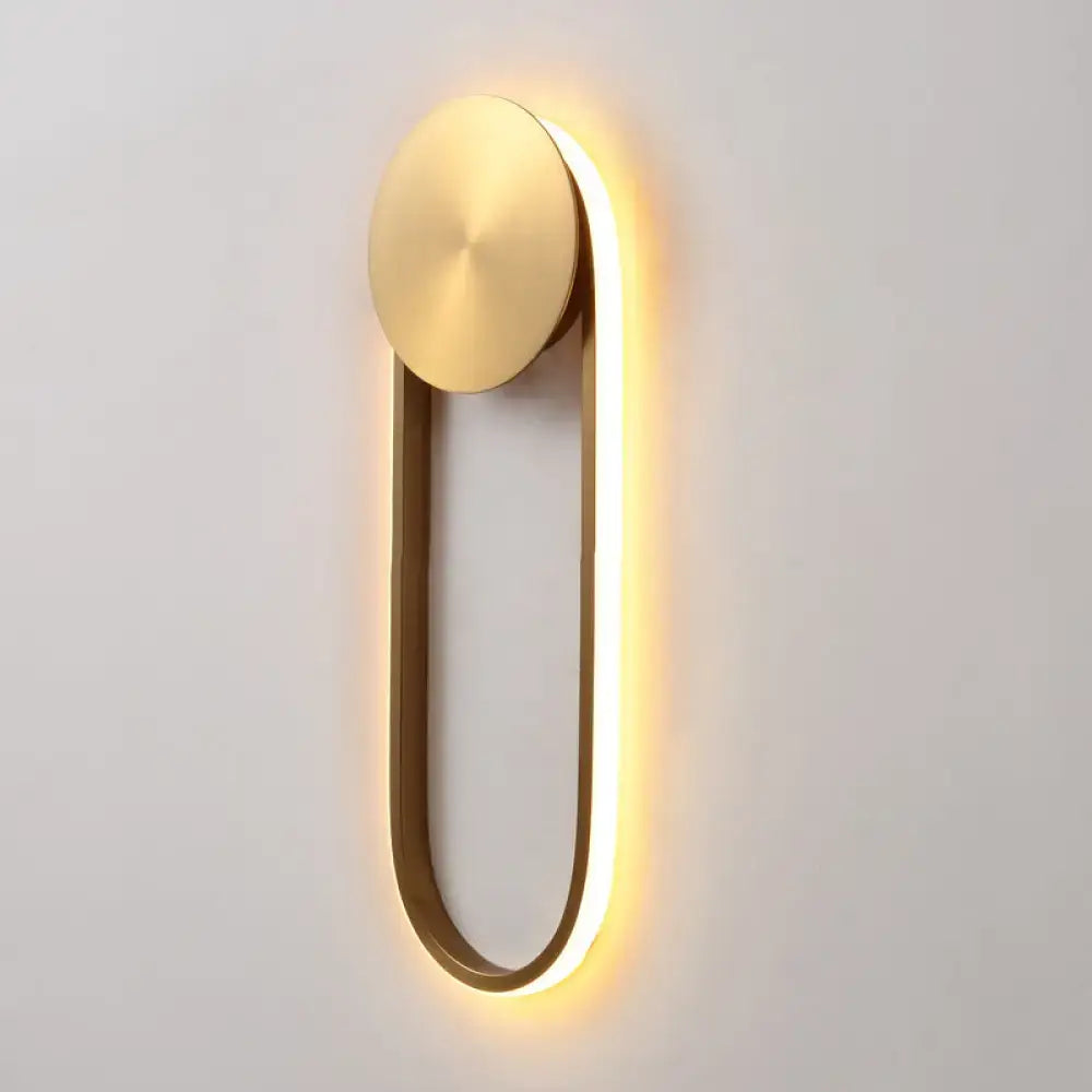 Modern gold-toned direct wired wall lamp with oval top plate and glowing led strip for bedroom lighting