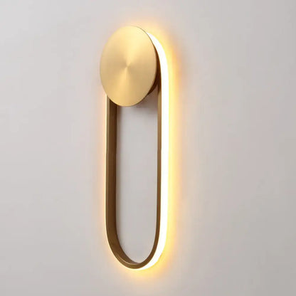 Modern gold-toned direct wired wall lamp with oval top plate and glowing led strip for bedroom lighting
