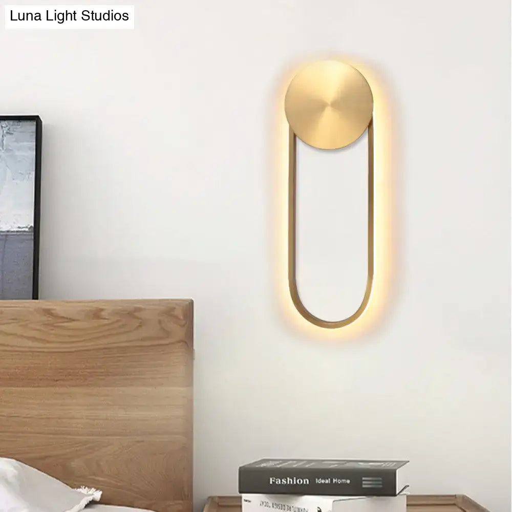 Modern gold-toned direct wired electric wall lamp with sleek oval design providing warm ambient bedroom lighting