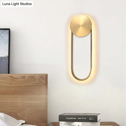 Modern gold-toned direct wired electric wall lamp with sleek oval design providing warm ambient bedroom lighting