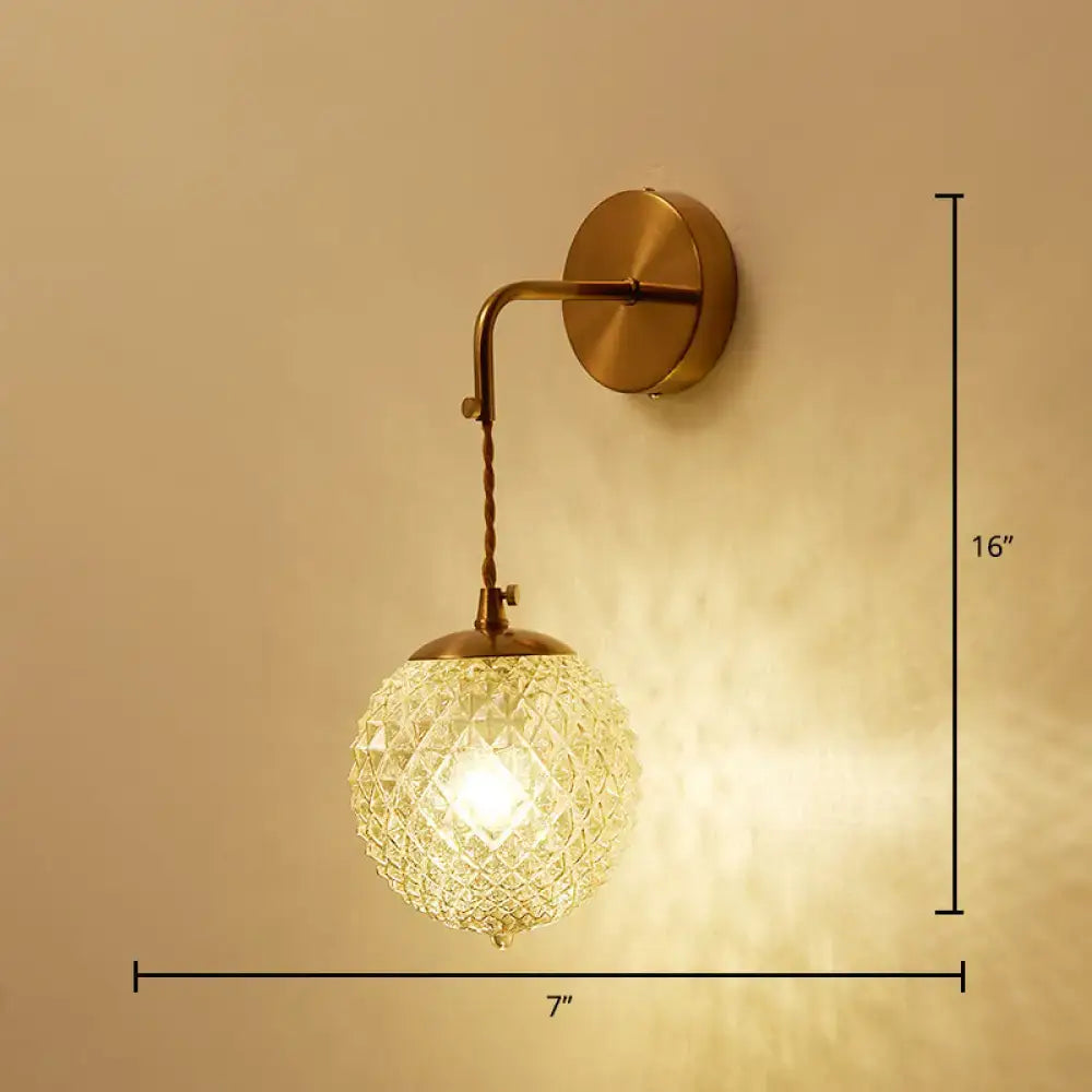 Postmodern gold ball shaped wall sconce with a vintage brass finish and a textured glass shade for bedroom lighting