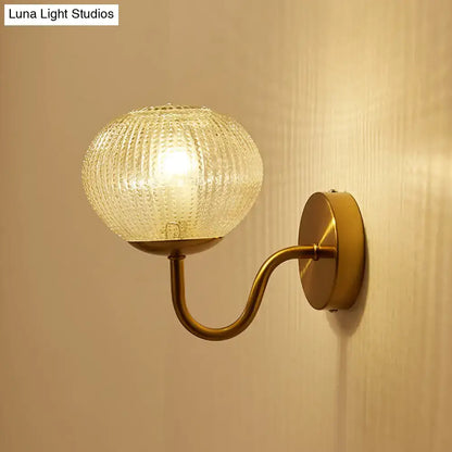 Vintage-style brass wall sconce with a postmodern gold ball shaped textured glass shade for bedroom lighting