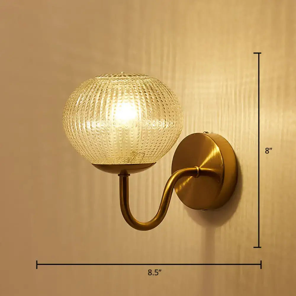 Antique brass ball shaped wall sconce with a textured glass shade and frosted textured glass globe for bedroom lighting