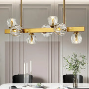 Gold-toned pendant light with clear faceted crystal globe shades featuring gold branch design for island lighting