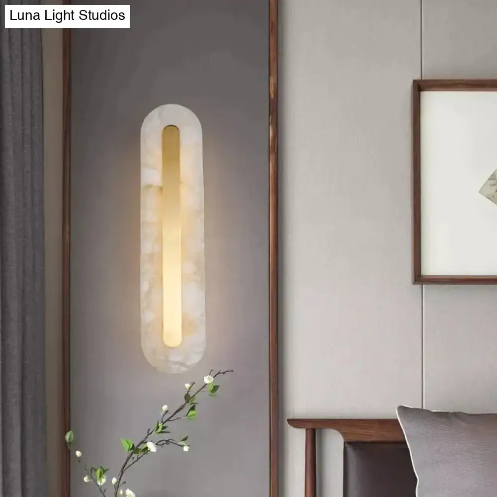 Postmodern gold copper marble wall lamp with a warm glowing light in a translucent white stone oval frame for living room