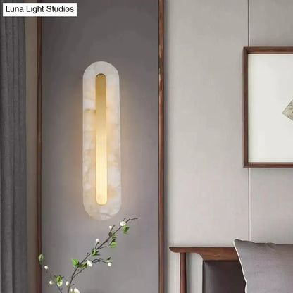 Postmodern gold copper marble wall lamp with a warm glowing light in a translucent white stone oval frame for living room