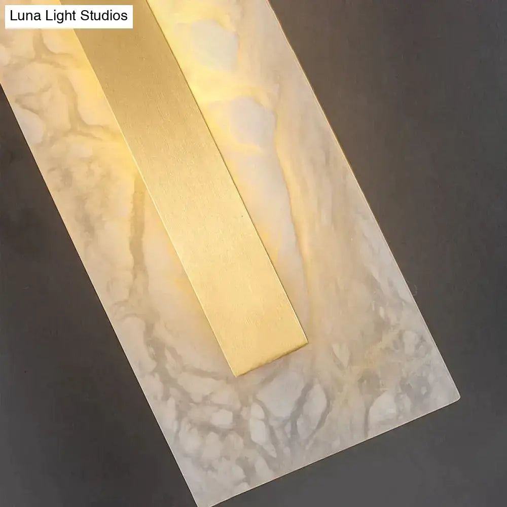 Postmodern gold copper marble wall lamp features a warm glowing metallic bar on a textured marble wall lamp backplate