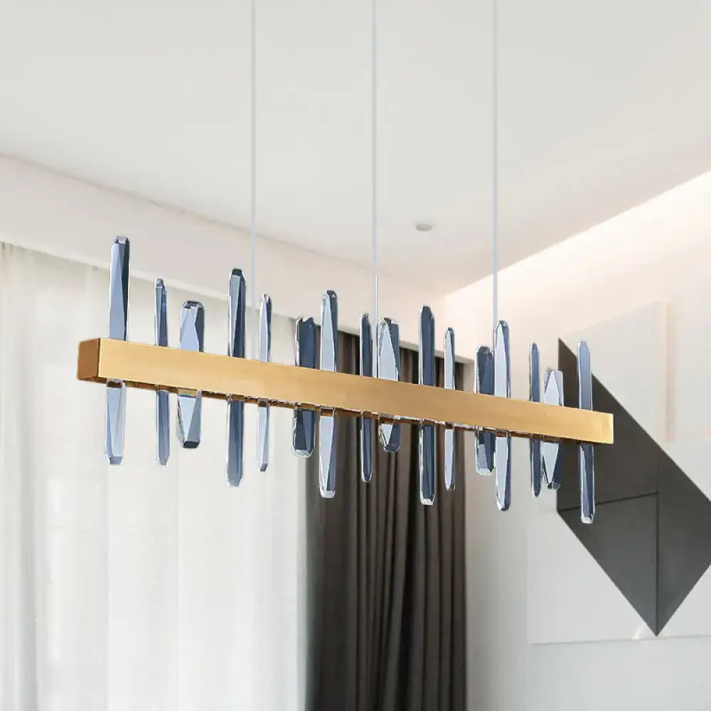 Modern gold crystal linear hanging island light with translucent blue glass prisms suspended by thin cords