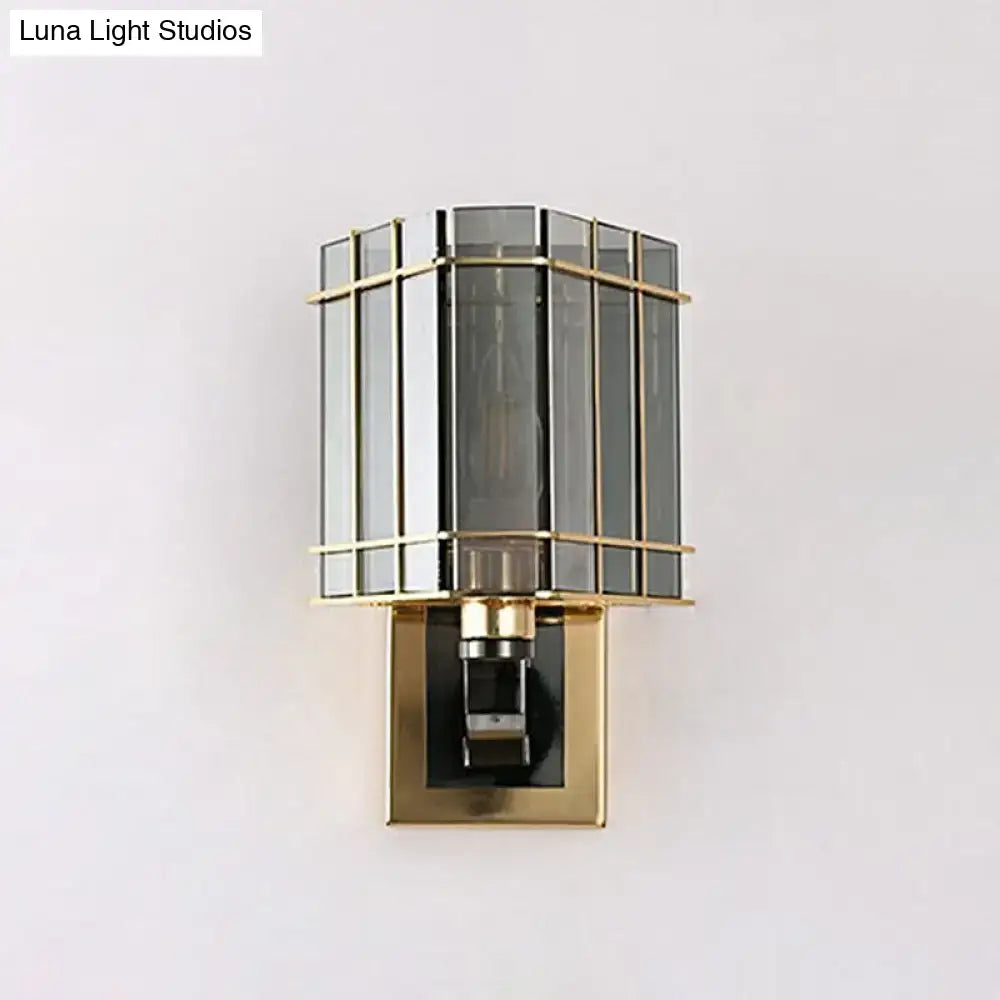 A chic wall light with a gold-toned metal frame and dark gray glass panels for modern living space lighting