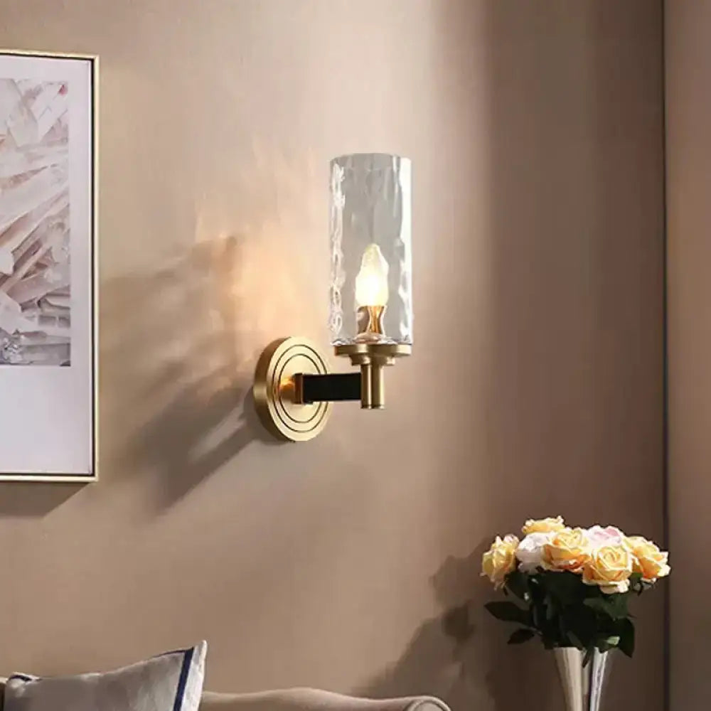 Brass-finished wall mounted light with textured glass cylinder and black accent bar for postmodern living room decor