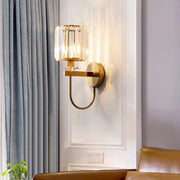 Gold-toned DecorBites™ postmodern wall sconce with cylindrical crystal shade and elegant curved arm design