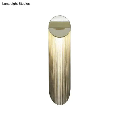 Postmodern gold fringed wall light fixture with sleek cylindrical design and cascading vertical strands for bedroom use